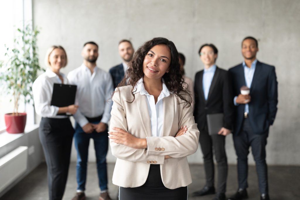 Businesswoman Standing In Front Of Her Employees Posing In Office