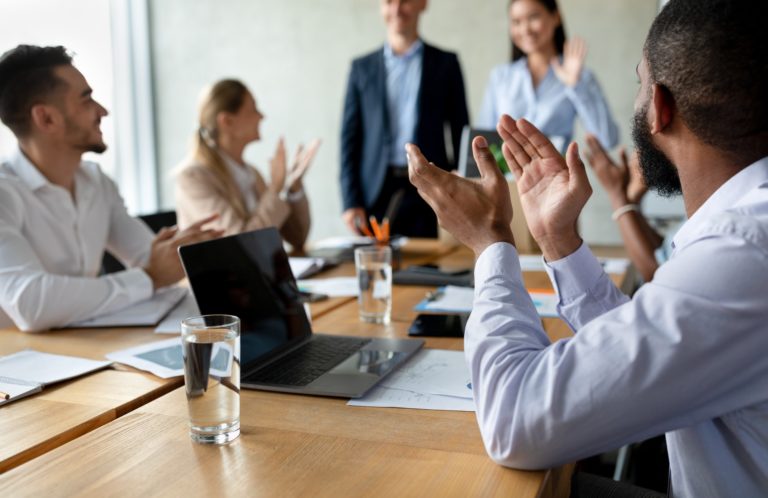 Group Of Colleagues Applauding During Meeting In Office, Greeting New Team Member