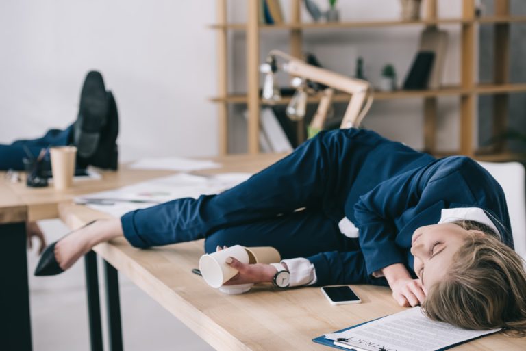 overworked businesswoman sleeping on table at messy office
