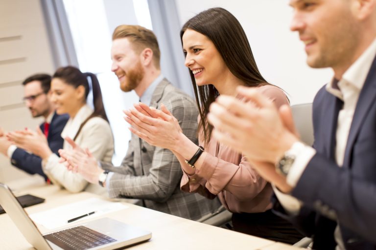 Young business people clapping their hands in office